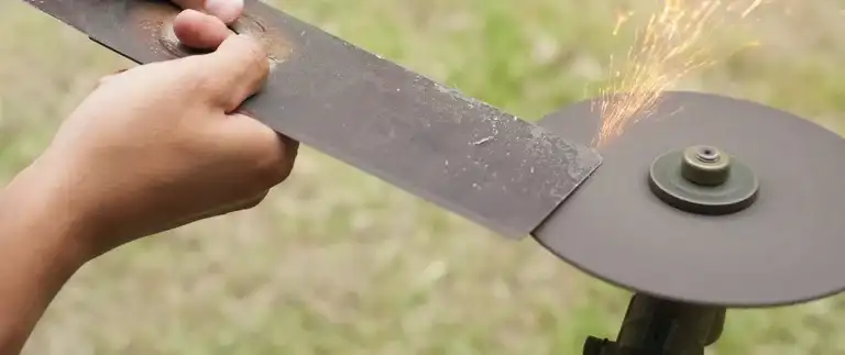 Person sharpening a lawn mower blade