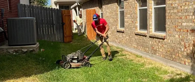 Lawn care crew mowing and trimming a backyard lawn in White Settlement, TX
