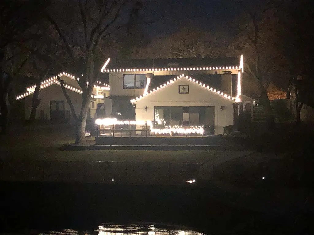 Holiday lights outlining rooflines and porch of a Fort Worth home at night