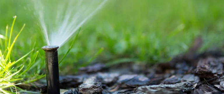Pop-up sprinkler head watering green lawn in Richland Hills, TX