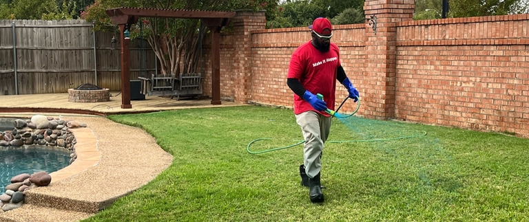Lawn care technician spraying treatment on a backyard lawn in Bedford, TX