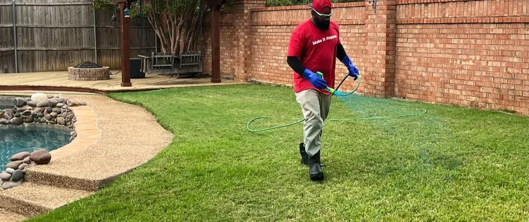 Lawn technician spraying fungicide treatment on backyard turf in Fort Worth