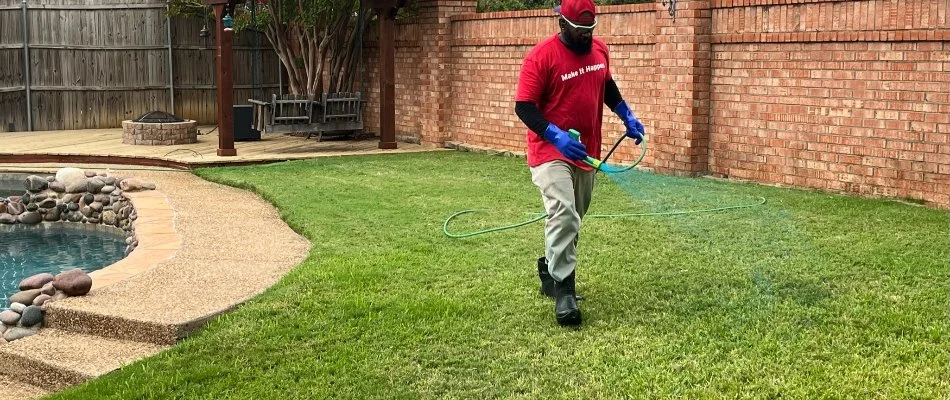 Worker spraying a lawn in Keller, TX, with a fertilizer treatment.